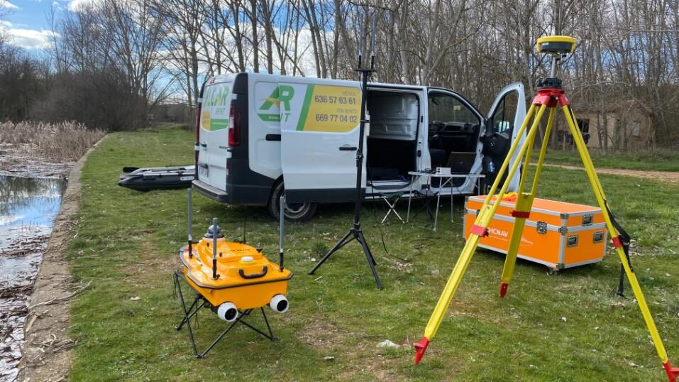 Equipos de topografía y batimetría de alta precisión junto a vehículo técnico en entorno natural.